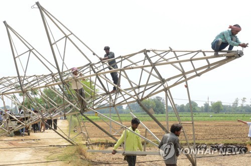 ▲ 13일 인도 북부 암리차르 외곽 마을에서 주민들이 강풍에 쓰러진 송전탑을 제거하고 있다.
