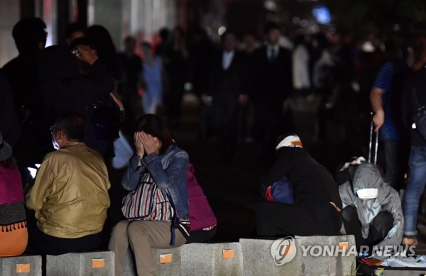 ▲ 시민들이 지진으로 정전이 발생한 삿포로 시내에서 피곤한 모습으로 길가에 앉아있다.