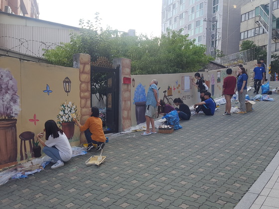 ▲ 대학생 봉사자와 주민들이 담장에 금연벽화를 그리고 있다. ⓒ 서울 성동구