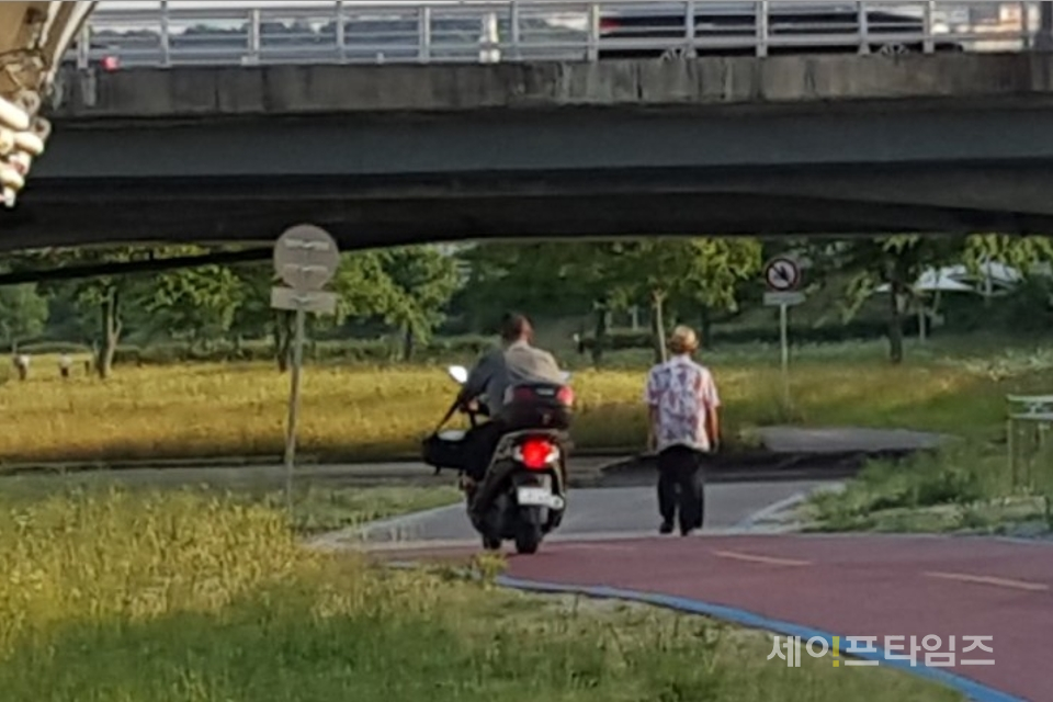 ▲ 대전 유성구 갑천변 자전거 전용도로에 오토바이를 탄 남성이 한 어르신 옆을 아슬아슬하게 지나고 있다. ⓒ 남철우 기자