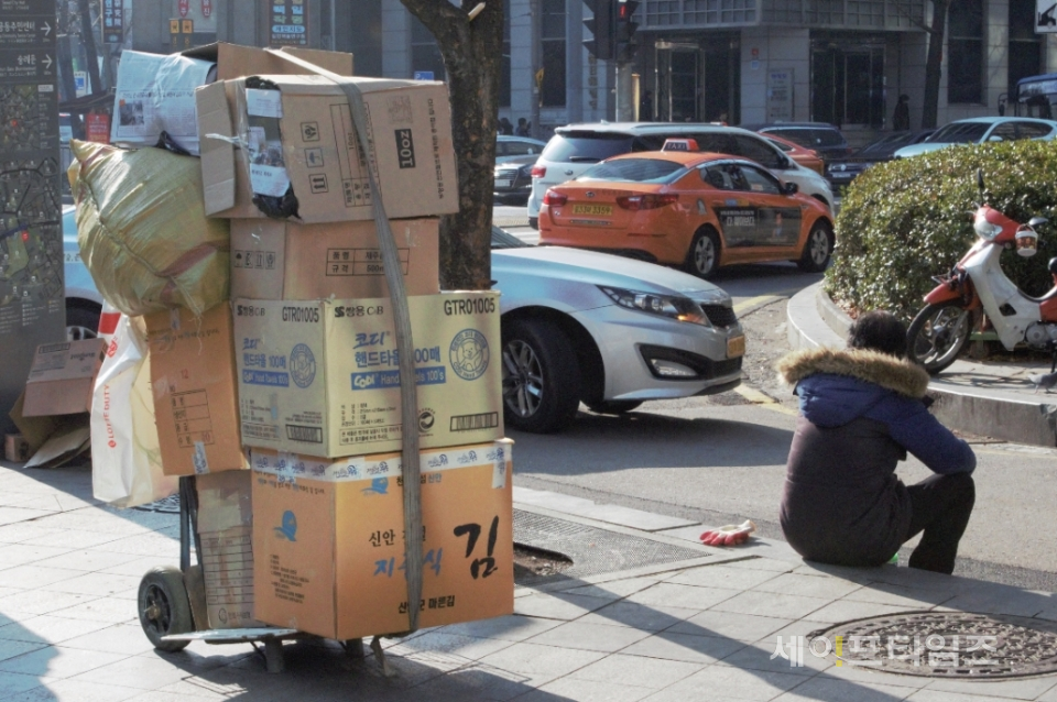 ▲ 서울시 중구 한 거리에서 폐지를 모은 행인이 앉아서 쉬고 있다. ⓒ 김희리 기자