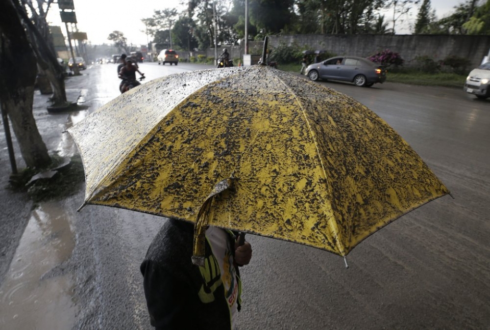 ▲  12일(현지시간) 필리핀 타가이타이에서 타알 화산이 폭발하면서 필리핀 주민이 화산재가 떨어지지 않도록 우산을 쓰고 있다. ⓒ AP