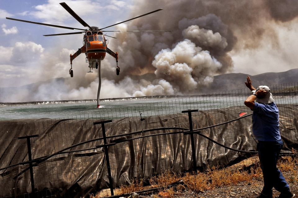 ▲ 23일 그리스 코린트 인근 스파토부니 마을 인근에서 산불이 나면서 헬리콥터 한 대가 탱크에서 물을 가득 채우고 있다. ⓒ 연합뉴스