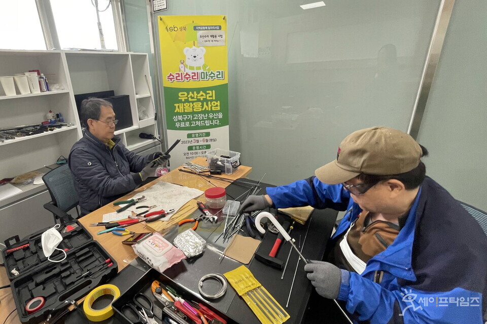 ▲ 수리 기술자들이 고장난 우산을 고치고 있다. ⓒ 성북구