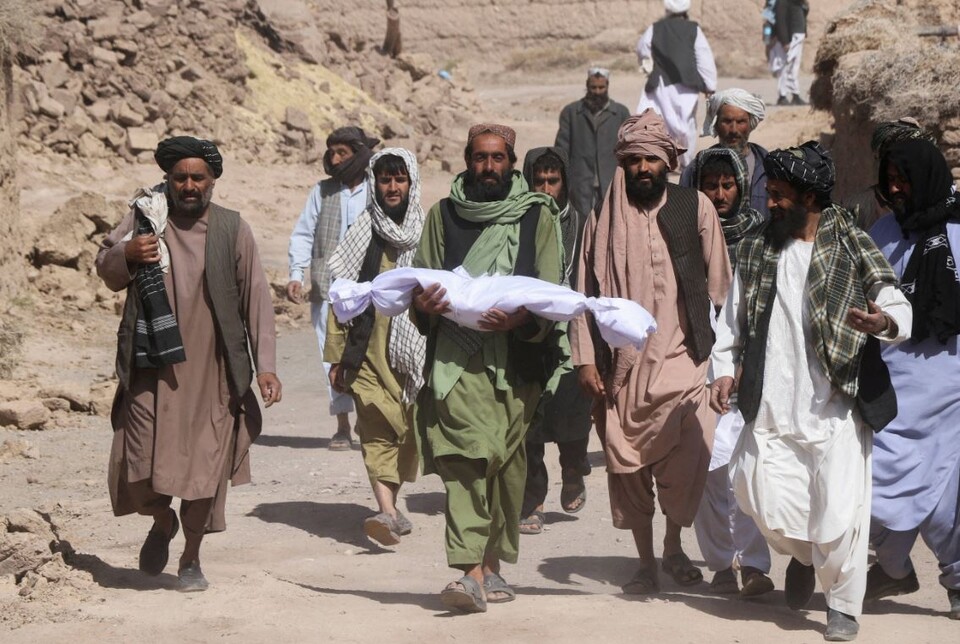 ▲ 지난 8일(현지시간) 아프가니스탄의 한 남성이 지진에 목숨을 잃은 자신의 아이의 시신을 들고 걸어가고 있다. ⓒ 로이터 통신