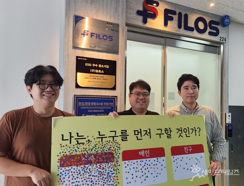 ▲ CHEOLSEUNG KIM, CEO of Filos, (center) poses with employees with an event board held at the safety industry fair. ⓒ Reporter Kim Ju-heon