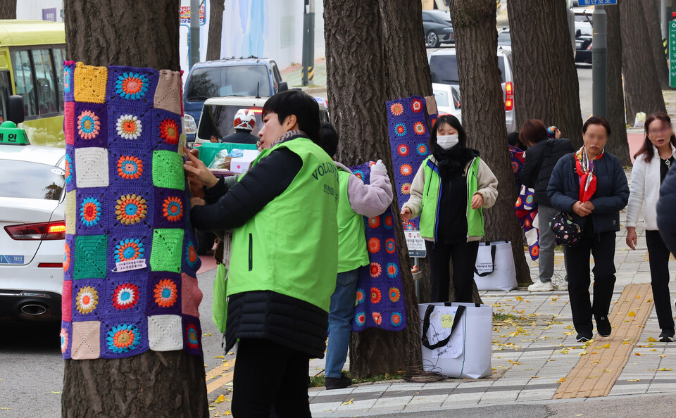 ▲ 22일 오후 인천시 미추홀구청 앞 거리 가로수에 자원봉사자들이 뜨개질로 만든 털실 겨울옷을 입히고 있다. ⓒ 연합뉴스