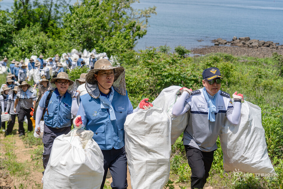 ▲ 김종욱 해양경찰청장(오른쪽)과 전중선 포스코이앤씨 사장이 인천 옹진군 자월도 갑진모래해변에서 수거한 쓰레기를 옮기고 있다. ⓒ 해양경찰청