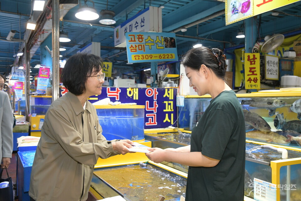 ▲ 오유경 식약처장이 12일 마포농수산물시장에서 한 상인에게 식중독 예방 홍보물을 건내고 있다. ⓒ 식약처