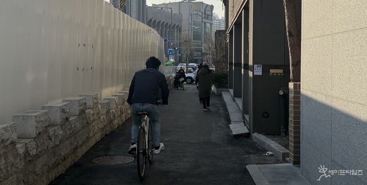▲ 23일 서울 성북구 종암동 지하철 공사 현장과 건물 사이 차도에 시민들이 자전거를 타거나 걸어가고 있다. ⓒ 민지 기자