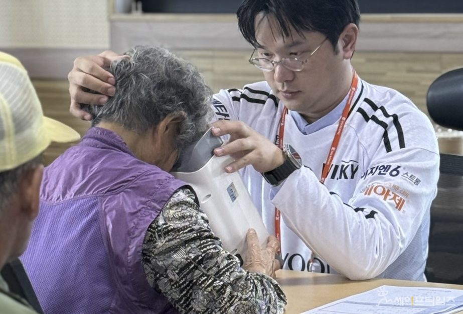 ▲ 대웅제약 의료봉사단이 강원 홍천 영귀미면 주민에게 위스키와 옵티나를 활용해 안저검진을 하고 있다. ⓒ 대웅제약